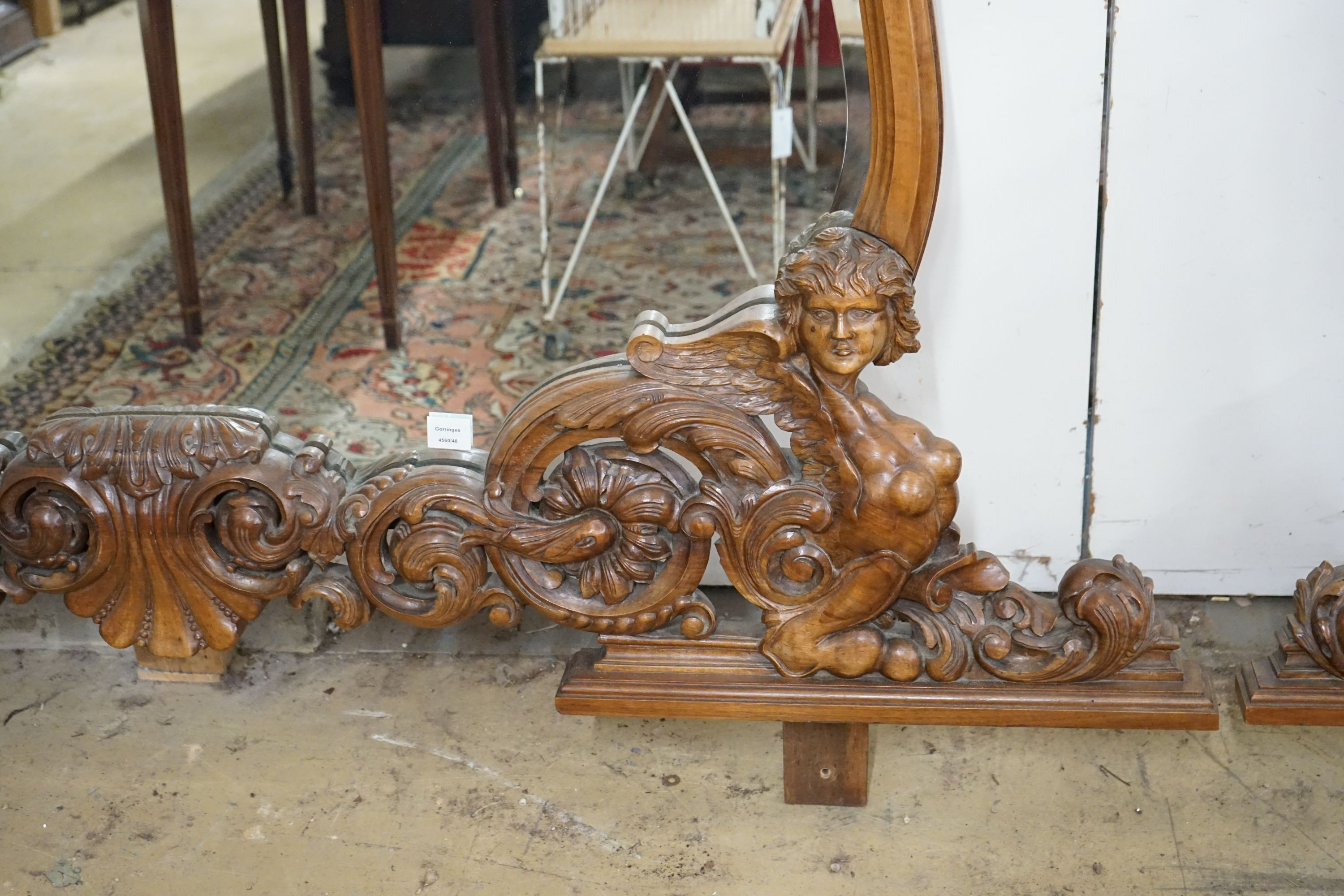 A near pair of Italian style carved walnut overmantel mirrors, decorated with winged figures, scrolls and scallop shells, larger width 200cm, height 152cm